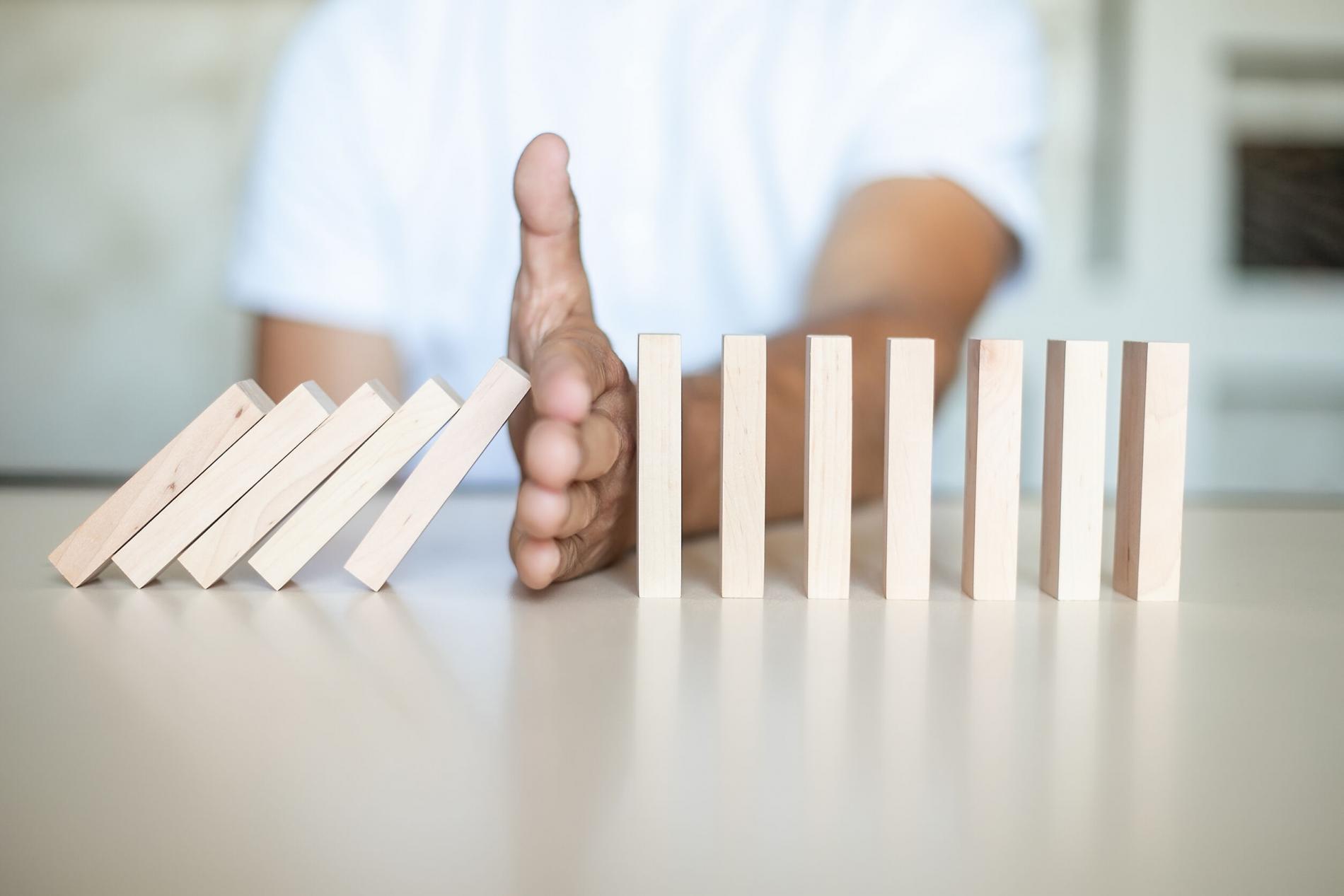 Hand stoping falling dominoes