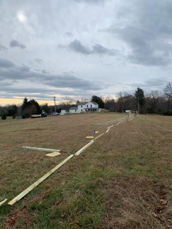 Image of a partially-built fence with a house in the distance