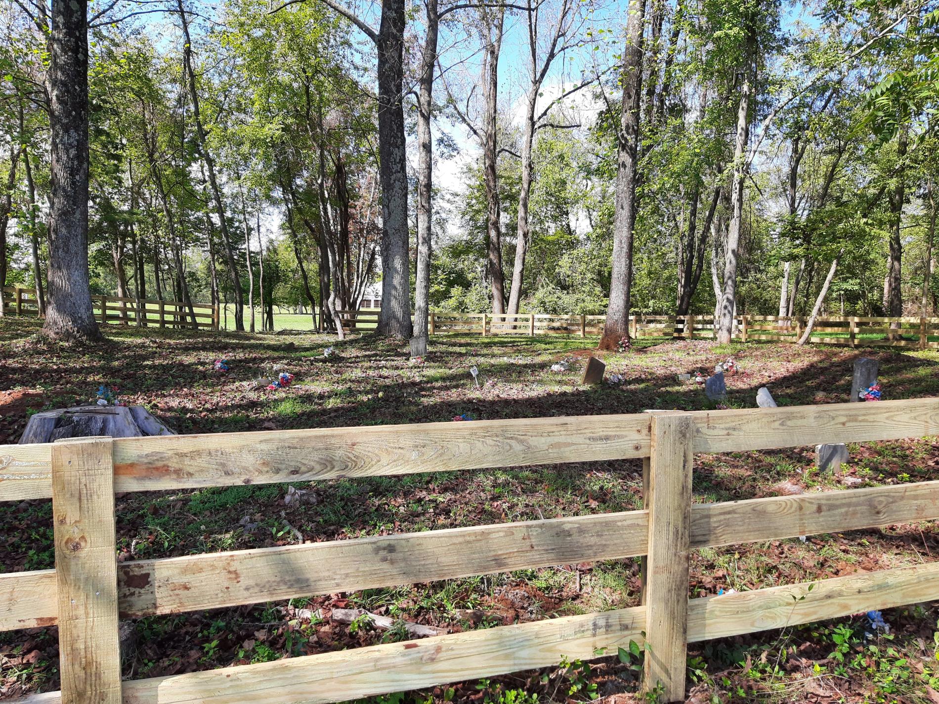 Image of a fence enclosing trees and headstones in a cemetery