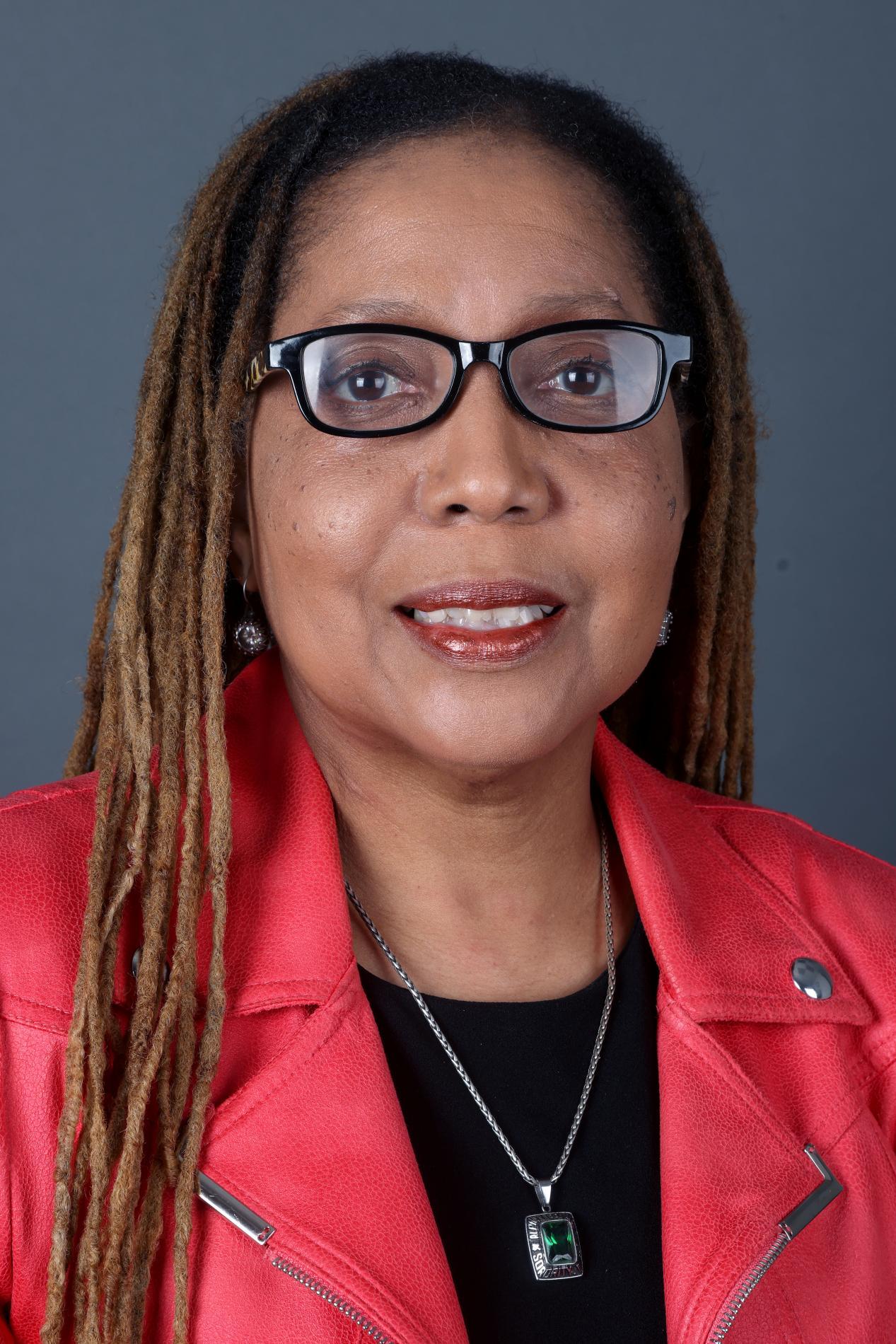 Headshot of an African American woman, facing forward, long hair, in a red suit jacket