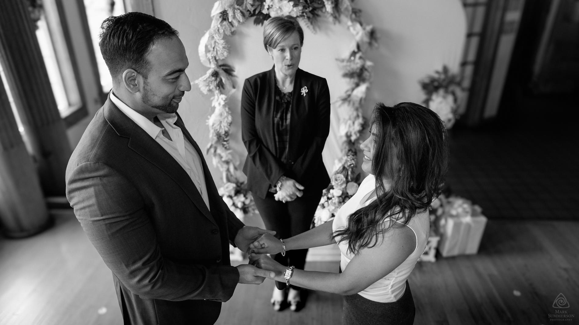 A photo of a couple exchaning vows during their civil ceremony; the Clerk of the Circuit Court, Jacqueline Smith is officiating.