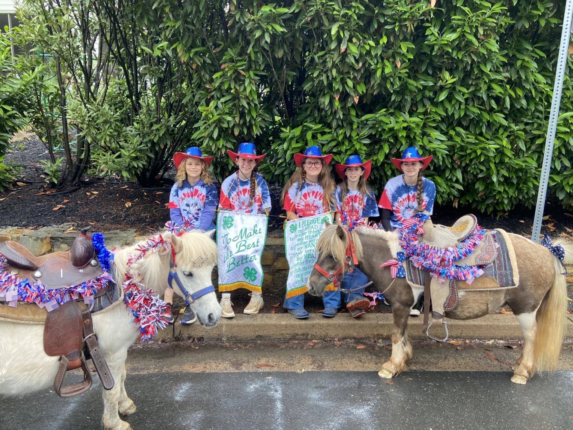 Nokesville 4-H Club members wearing blue and red cowboy hats and with two ponies getting ready to march in a parade.