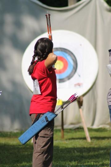 Prince William 4-H'er aiming a bow and arrow at a target.