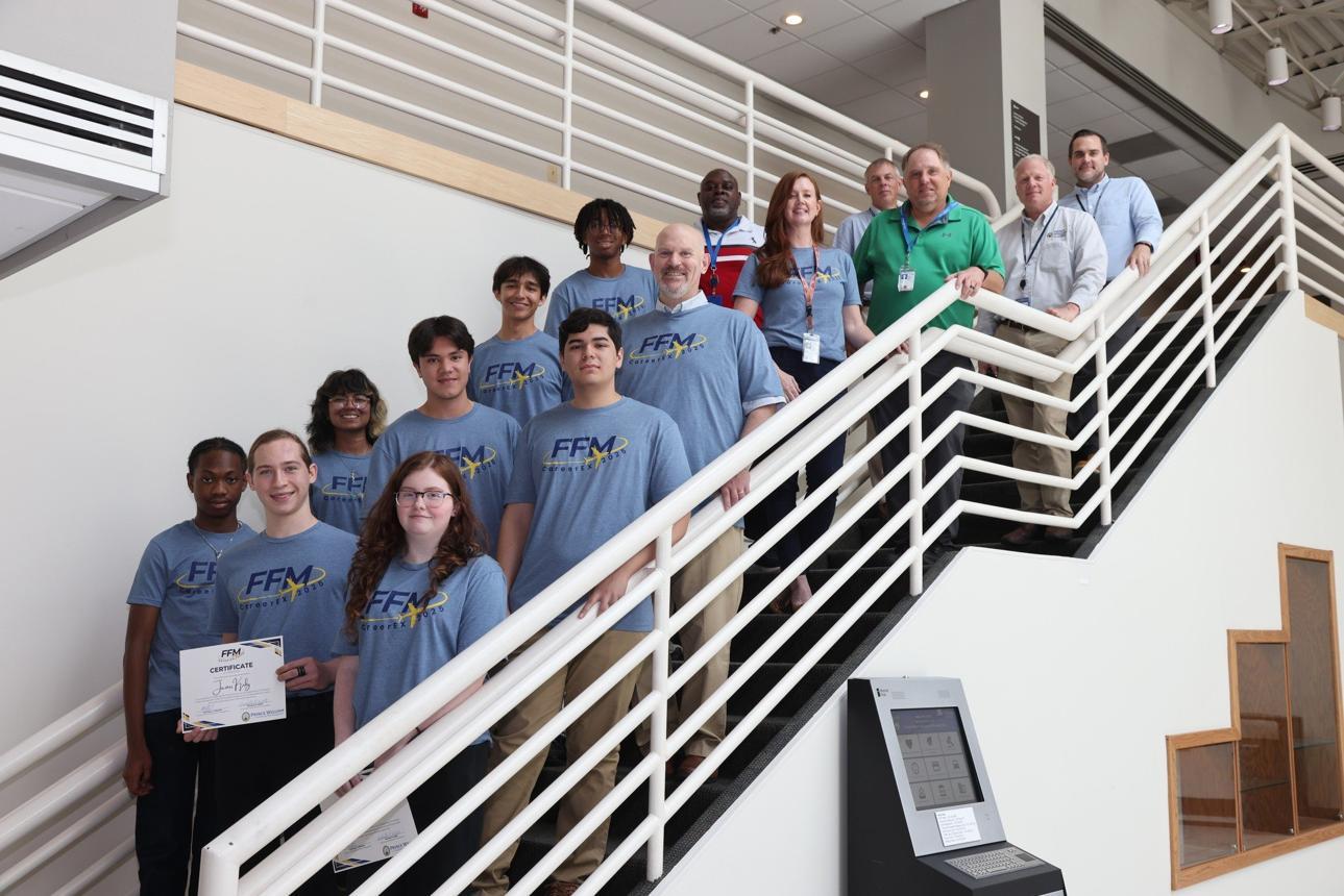 A group of people in blue shirts standing at varying heights on stairs